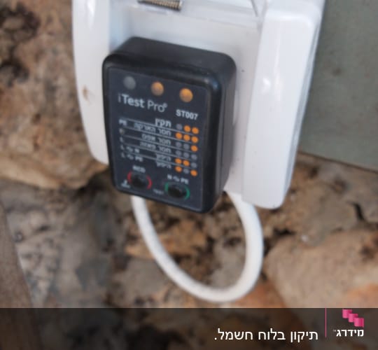 בודק חשמל מחובר לשקע עם כיסוי פלסטיק שקוף